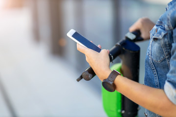 Young woman with electric scooter checking her smartphone