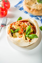Two portion homemade Chicago Pizza Pot Pie with cheese, minced beef meat and vegetables, with pots and ingredients on domestic table copy space