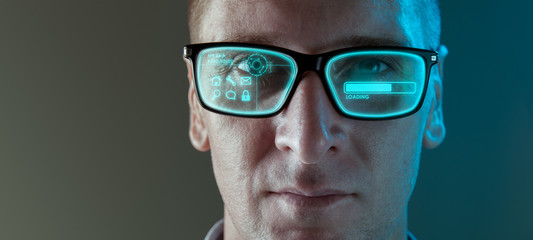 A close up image of a man wearing smart arugmented reality glasses with virtual screen displaying...