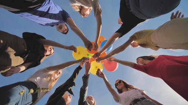 A group of friends release colorful balloons into the sky.