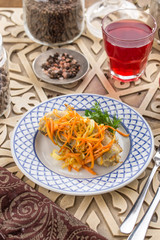 Fried cod with vegetables and glass of red drink on oriental wooden table