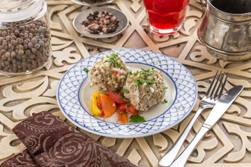 homemade meatball stuffed with rice and baked vegetables on white plate on oriental wooden table