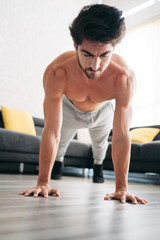 Fototapeta na wymiar Adult Man Training Chest Muscles At Home Doing Push-Ups