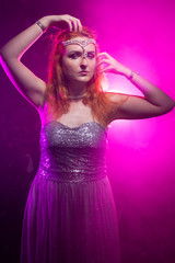 fashion chubby woman posing in trendy glitter dress alone in the night party with neon light and smoke