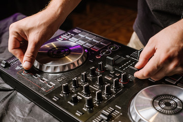 DJ plays on a mixer in the club on black background