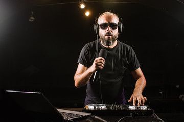 DJ plays on a mixer in the club on black background