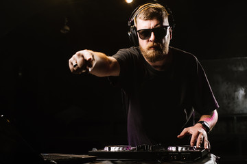 DJ plays on a mixer in the club on black background