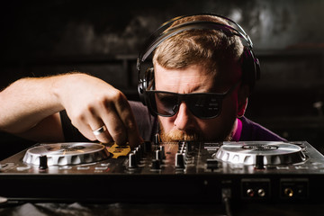 DJ plays on a mixer in the club on black background