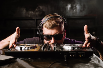 DJ plays on a mixer in the club on black background