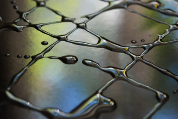 Water and oil droplets in the form of art inscriptions on a black metal surface with light...