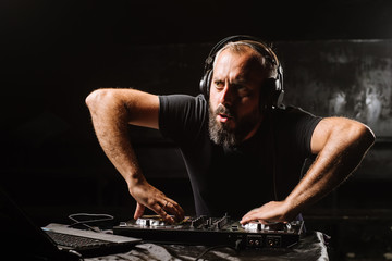 DJ plays on a mixer in the club on black background