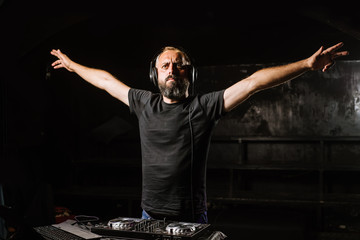 DJ plays on a mixer in the club on black background