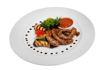 Grilled sausages with zucchini and sauce on a plate on a white isolated background