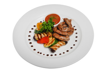 Grilled sausages with zucchini and sauce on a plate on a white isolated background