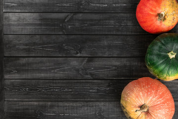 Autumn composition with green, yellow, red and orange pumpkins on black wooden background. Flat lay, top view, copy space