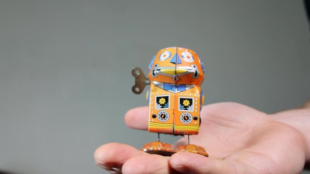 4K man holding vintage tin wind up walking robot toy