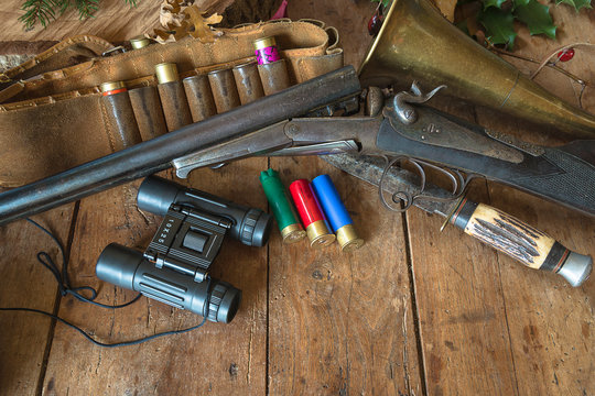 Hunting stille life. Old hunting rifel, cartridges, binoculars, knife and hunting belt on the rustic wooden background with copy space