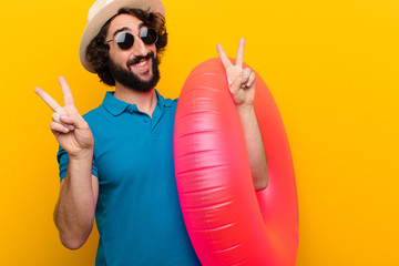 young crazy man smiling and looking happy, friendly and satisfied, gesturing victory or peace with...