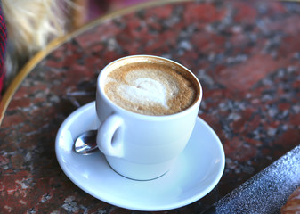 a cup of aromatic coffee stands on a marble table in a cafe