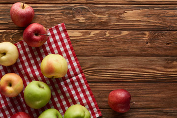 top view of checkered tablecloth with fresh apples on wooden surface with copy space