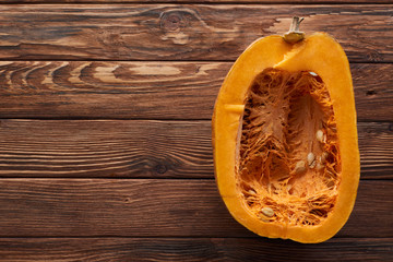 top view of ripe pumpkin half on brown wooden surface