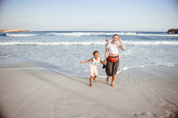 Family walking on the evening beach during sunset. Child with mom.