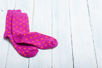 pair of magenta socks with orange dots on white wooden