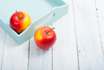 apples at blue tray, white wood table