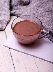 Cup of hot coffee or hot Chocolate on rustic wooden table, closeup photo warm sweater with mug, winter morning concept, top view