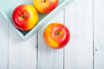 apples at blue tray, white wood table