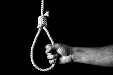 Hand near the noose on black background. Suicide concept. Hanging because of work stress. Depression of burnout. Terrible life situation.