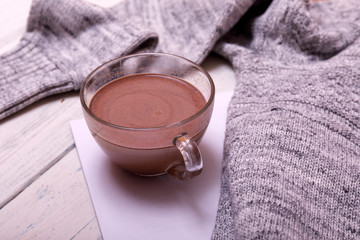 Cup of hot coffee or hot Chocolate on rustic wooden table, closeup photo warm sweater with mug, winter morning concept, top view