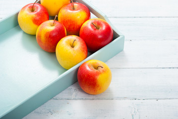 apples at blue tray, white wood table