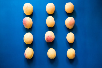 Many  apricots on a blue background. Flat lay composition with hard light