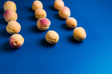 Many  apricots on a blue background. Flat lay composition with hard light
