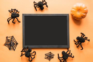 Halloween holiday blank with party decor, black spiders, web on orange. Flat lay, top view. Space for text