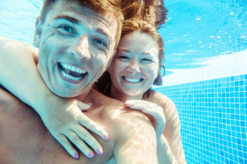 glückliches und lustiges Paar unter Wasser im Schwimmbad