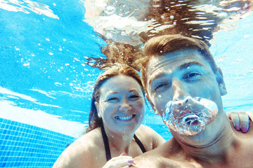 glückliches und lustiges Paar unter Wasser im Schwimmbad