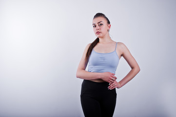 Cheerful attractive young fitness woman in top and black leggings isolated over white background.