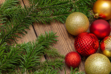 Fur spruce pine coniferous branches, sparkling shiny toys balls on the brown brushed wooden background