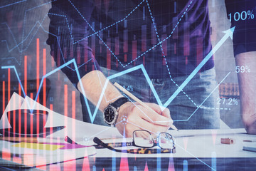 Double exposure of man writing on paper with forex graph.