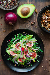 salad on a black matte plate: arugula, figs, avocado, red onions, cucumbers, walnuts, viburnum, thyme, spices
