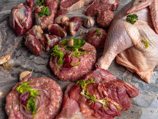 background of fresh raw meat. Different types of raw pork meat, chicken, beef, turkey giblets with herbs on dark marble, copy space