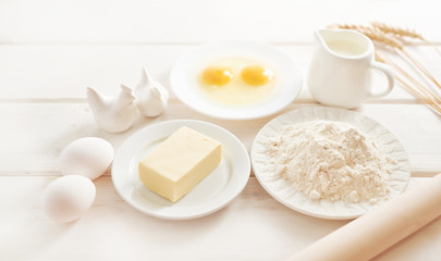 Fototapeta na wymiar flour, eggs, butter and milk on a white wooden background, ingredients for baking