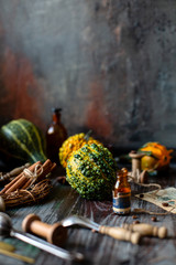 assorted mini pumpkins on rustic wooden table with cinnamon sticks, bottles, spoons opposite concrete wall, selective focus, thanksgiving card