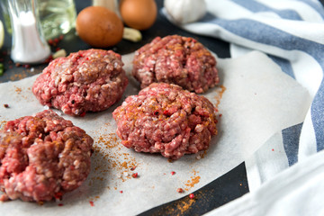 4 meat burgers, pork round cutlets with spices on a black background, eggs, schnitzel,