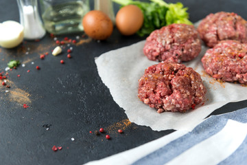 raw pork burgers on a black background, meat cutlets