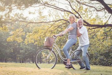 Couples elderly are bicycling together.