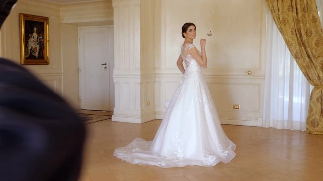 Beautiful model in white glamour bridal dress posing Photographer