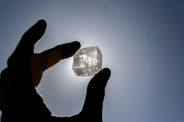 Silhouette hand holding a crystal in front of the sun
